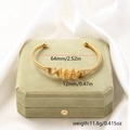 Macro detail of golden wire wrap bracelet with dimensions 64mm and 12mm on silk fabric - Woven Wrapped Style (Gold#1)