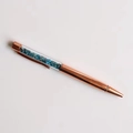 Detailed macro view of rose gold crystal ballpoint pen filled with blue crushed stones - Apatite