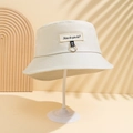 Dettaglio del cappello a secchiello bianco sporco con anelli in metallo e ricamo di lettere - M (56-58cm) / Beige