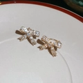 Vista macro di un earcuff a fiocco dorato con zirconi incastonati su piatto di porcellana - Coppia d'oro