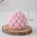 Roze bolvormige geurkaars met wit label op een natuurlijke houten basis - Ronde Bellenbal (Witte Perzik Oolong) / Roze