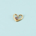 Gros plan d'un pendentif cœur doré serti d'une pierre violette sur fond bleu clair - Or Février