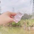 Detailopname van een transparante roze glitter beer telefoonhouder tegen een buitenachtergrond - Uitbreidbare Standaard / Roze Glitter Beer