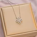 Silver clover pendant necklace featuring sparkling zircon pave setting on a jewelry box - 6047 Hollow Clover / Silver White Zircon
