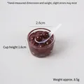 Miniatuur transparante kom met donkere parels dessert en kleine witte lepel - Bruin