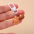 Dettaglio del portachiavi a forma di tartaruga in resina arancione con ghianda marrone - Marrone