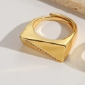 Nahaufnahme eines goldfarbenen Rings mit Zirkon-Inlay auf Marmor-Hintergrund - Geometrisch Glatt