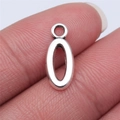 Silver oval alloy pendant for DIY jewelry making shown between fingertips for scale - Letter O (B15668) / Antique Silver