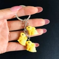 Dettaglio di tre ciondoli a forma di coniglio in resina gialla su portachiavi metallico - Giallo
