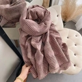 Bufanda de cachemira con pata de gallo rosa y pompones en silla beige para estilo de invierno - Caqui