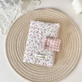 Pink floral fabric book cover with heart button and checkered strap on a woven mat - Twill Floral Pink
