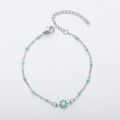 Detail of silver chain bracelet featuring blue enamel daisy charm and matching beads - Steel + Lake Blue