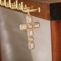 Primo piano del ciondolo a croce dorata con zirconi su un supporto di legno - Stile Croce 7