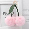 Détail de porte-clés cerise en fausse fourrure rose avec feuilles en cuir vert et fermoir doré - Rose Clair