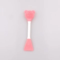Detail of pink silicone facial brush with bear-shaped massage bristles and mask spatula - Deep Pink