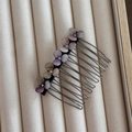 Detail van de haarkam met paarse en roze bloemstenen op een zachte beige fluwelen basis - Roze