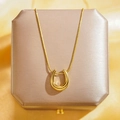 Élégant pendentif fer à cheval doré sur chaîne serpent posé sur un écrin à bijoux - Or Lisse Fer à Cheval