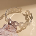 Detalle del brazalete de metal plateado calado con forma de corazón y textura martillada - Plateado