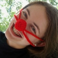Close-up of a funny red handmade crochet nose warmer worn by a smiling woman outdoors - 5CM Diameter / Red