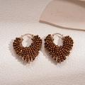 Macro shot of retro brown beaded heart earrings with intricate handmade weaving texture - Brown