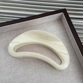 Dettaglio molletta per capelli a mezzaluna in acetato avorio marmorizzato su vassoio - Beige