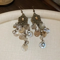 Makroansicht der Vintage-Ohrhänger mit hohlem Bronze-Design und Anhängern aus Muscheln - Ohrhaken - Silber-Bronze