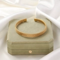 Detailed view of golden twisted braided cuff bracelet on green velvet jewelry box - Transverse Textured Style / Gold 4