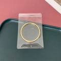 Goldener Ring in einem transparenten PVC-Schmuckbeutel auf einem dunkelgrünen Tablett - 8*12cm (10 Stück)