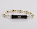 Detail of beaded Evil Eye bracelet with pearls, gold beads, and enamel charm - Black
