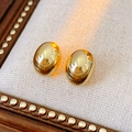 Close-up of golden oval mirror stud earrings on a beige textured soft cushion - Silver Needle / Real Gold Plated / Gold