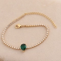 Détail macro d'un bracelet tennis doré serti de zircons et d'une pierre verte poire - Vert