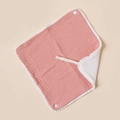 Detailed macro shot of soft pink cotton baby bib with pom-pom trim and snap buttons - Dusty Rose And White
