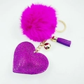 Close-up of pink pompom keychain with purple rhinestone heart, tassel and gold bell - Fuschia