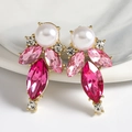Macro view of teardrop earrings with pink crystals and pearls on marble surface - Rose Red