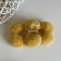 Detailed close-up of yellow plush hair claw clip featuring soft round pom pom texture - Yellow