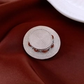 Dettaglio della spilla a forma di cappello d'argento su sfondo di raso rosso - 64# Cappello di Paglia Intrecciato Argento