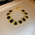 Dettaglio macro delle maglie nere geometriche sul bracciale dorato con chiusura a moschettone - Bracciale-Oro-Nero