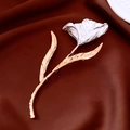 Détail d'une broche tulipe avec pétales argentés et tige dorée sur tissu brun - Or-Blanc