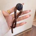 Detalle de pinza para el cabello en forma de S marrón oscuro con una gran perla negra - Gris Transparente con Perla Negra Profunda