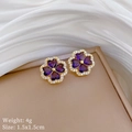 Close-up of gold-plated clover earrings with purple heart stones on a jewelry box - Purple Heart Clover Stud Earrings (D554)