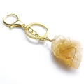 Detalle de llavero artesanal de cristal amarillo en bruto con alambre dorado y cierre de langosta - Citrino