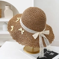 Dettaglio di un cappello di paglia con bordo in pizzo bianco e fiocchi decorativi - Cachi