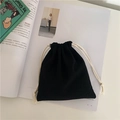 Macro shot of minimalist black cotton drawstring storage pouch on magazine background - Small / Black