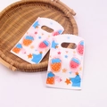 Mini plastic gift bag with strawberry and star prints on a woven wooden tray - No. 97 (Strawberry & Star)
