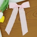 Close-up of pink satin bow hair clip with detailed stitching on wooden tray - Light Pink
