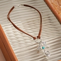 Detail of Western choker featuring brown suede cords with cactus, boot, and hat charms - Silver