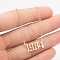 Detailed close-up of a gold gothic 1984 birth year number pendant on a fine link chain - 1984 / Gold