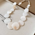 Close-up of elegant cream white shell beads necklace on a beige textured jewelry tray - 12# Necklace - White Shell