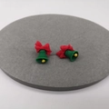 Festive Christmas bell earrings with red bow and green body on a grey display mat - Bell