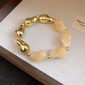 Schickes Retro-Armband mit geometrischen Perlen in Gold und Creme auf weißem Stoff - Weiß